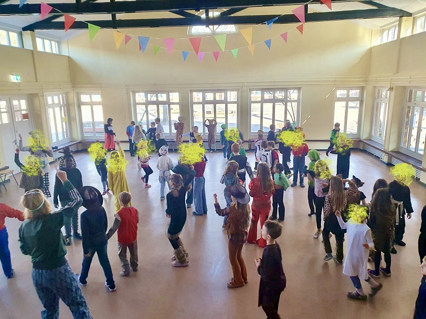 Hier sind Kinder zu sehen, die in der Aula tanzen.