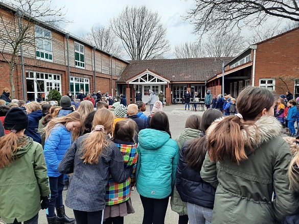 Hier sind Schulkinder zu sehen, die im Kreis stehen.