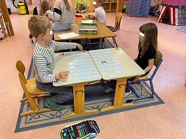 Hier sind zwei Kinder zu sehen, die Memory spielen.