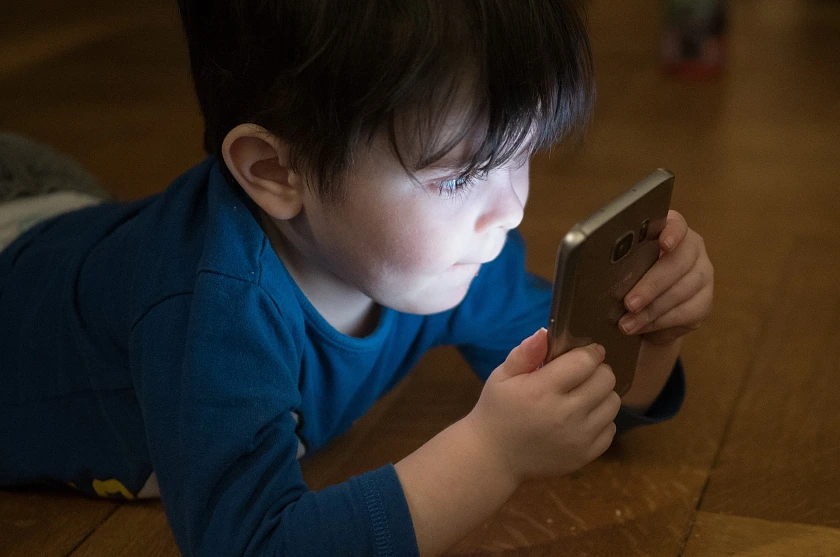 Hier ist ein kleines Kind zu sehen, das auf ein Smartphone schaut.