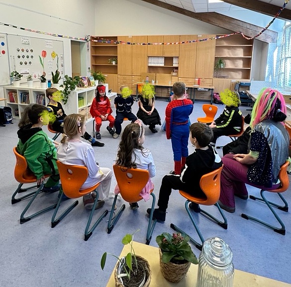 Hier sind Kinder zu sehen, die ein Spiel im Stuhlkreis spielen.