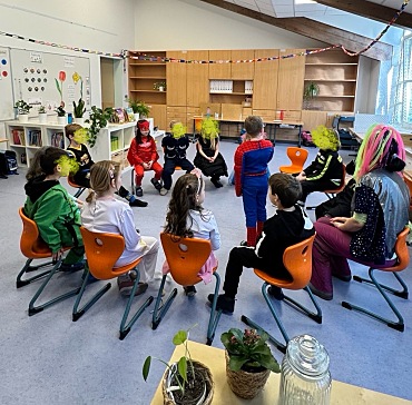 Hier sind Kinder zu sehen, die ein Spiel im Stuhlkreis spielen.