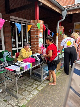 Hier sind Menschen zu sehen, die den Stand des Schulvereins betreuen.