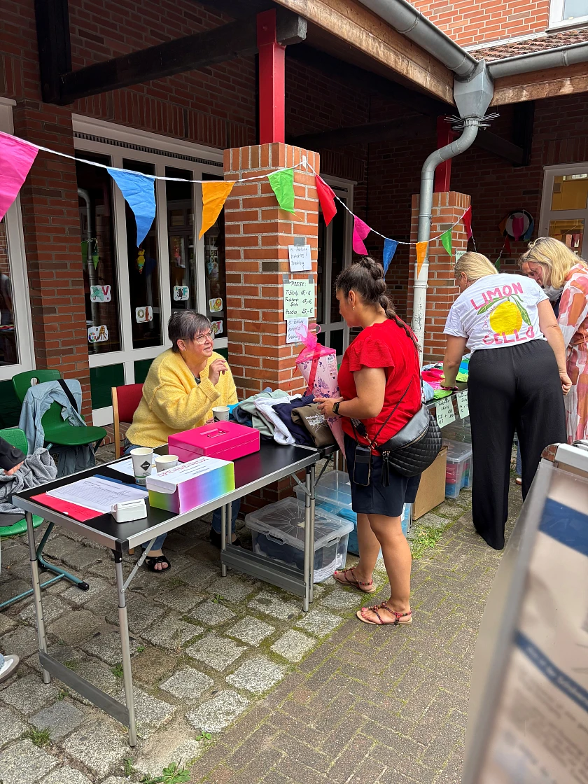 Hier sind Menschen zu sehen, die den Stand des Schulvereins betreuen.