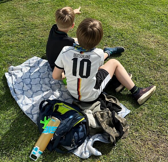 Hier sind zwei Kinder zu sehen, die auf einer Decke sitzen.