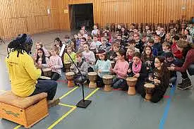 Hier ist eine Schulklasse zu sehen, die trommelt.
