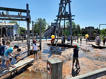 Hier sind Schüler zu sehen, die auf einem Wasserspielplatz spielen.